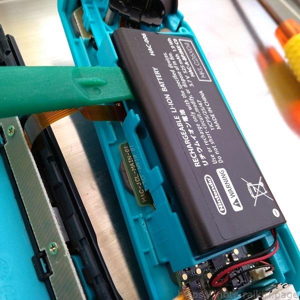 Nintendo Switch の Joy-Con(左) のバッテリーを緑の道具を使って持ち上げるところの写真